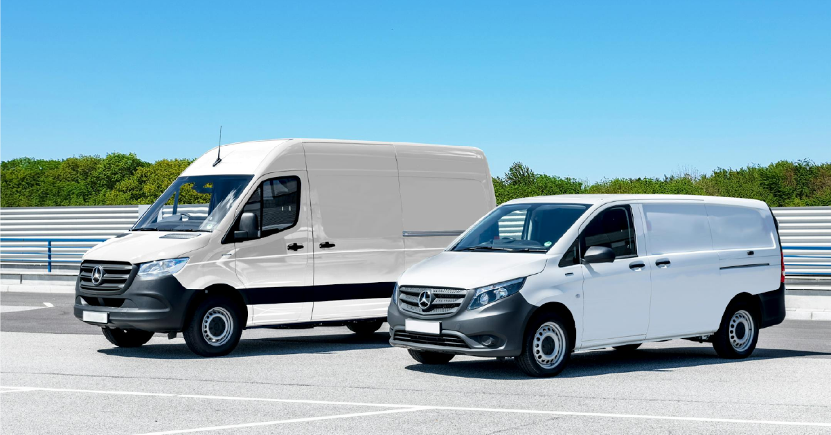One large white van parked beside a smaller white van on concrete under a clear blue sky.