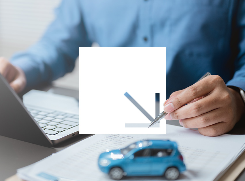 Person reviewing paperwork at a desk with a laptop and toy car.