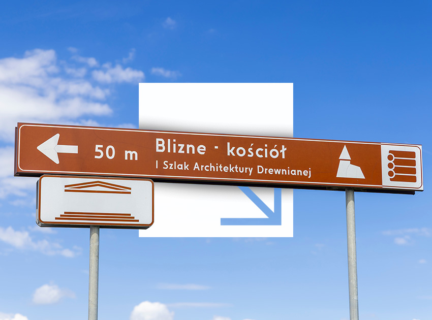 Directional Polish road sign against a blue sky, showing how to follow road markings in Poland when driving a hire car with excess insurance protection.