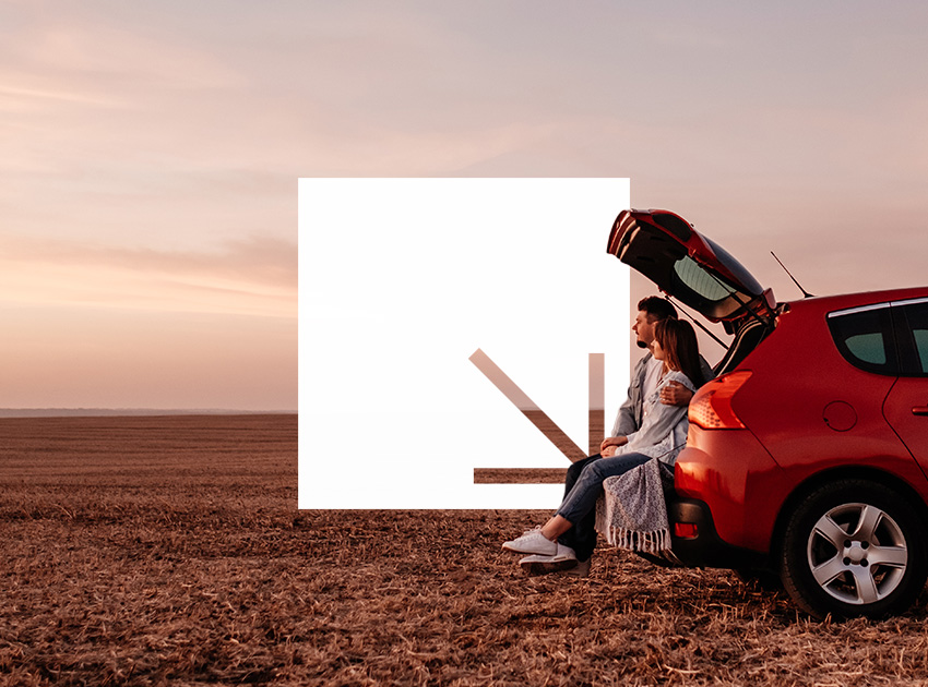 Couple sitting at the back of a car at sunset, symbolising the peace of mind offered by car hire excess insurance during European road trips.