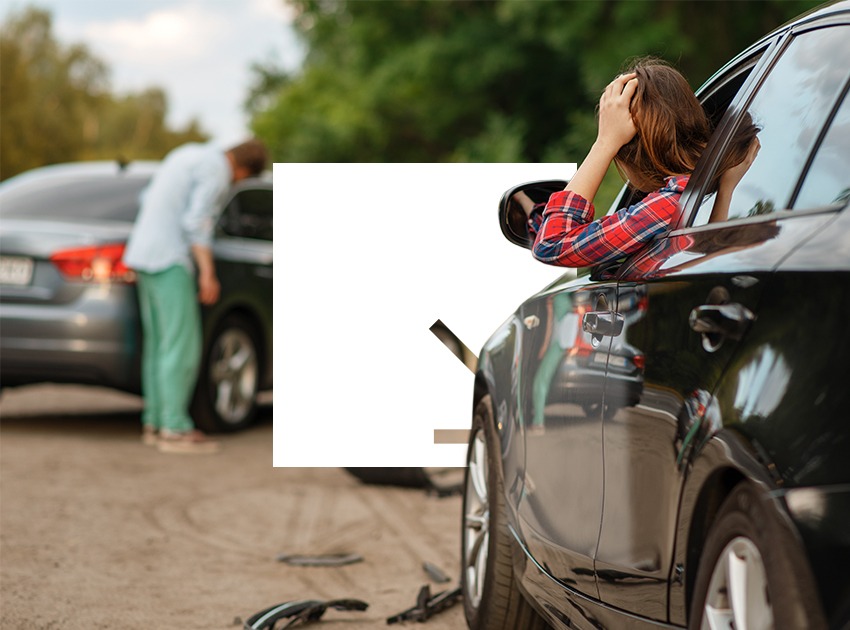Two cars are involved in a minor accident on a road surrounded by trees.