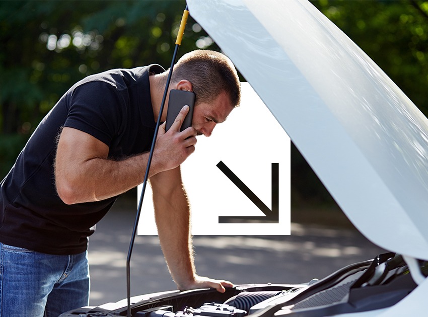 A man stands by the open hood of a car talking on a phone with a concerned expression.